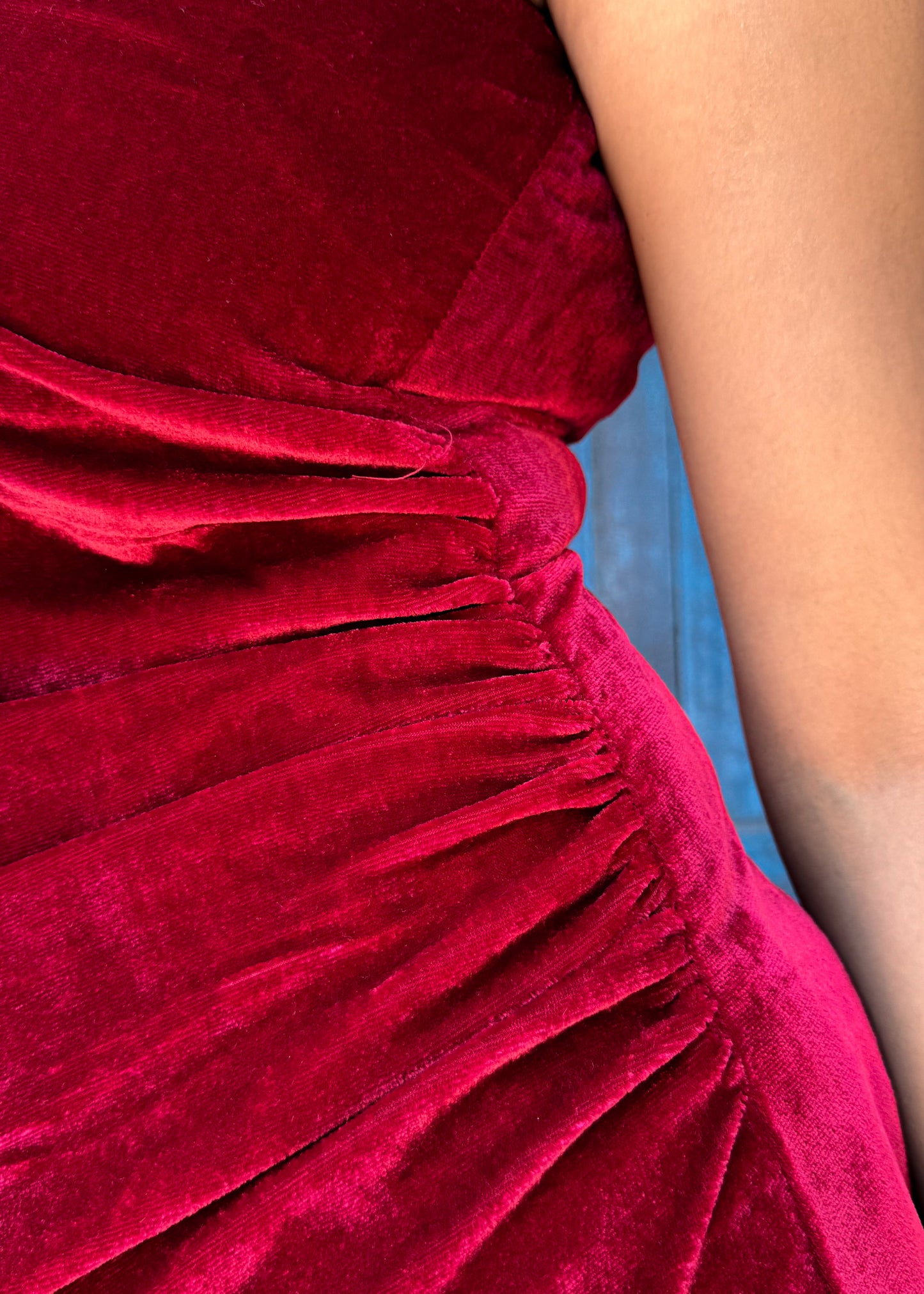 Close-up of the gathering detailing on the side of the deep red velvet Berry Blush slip dress.