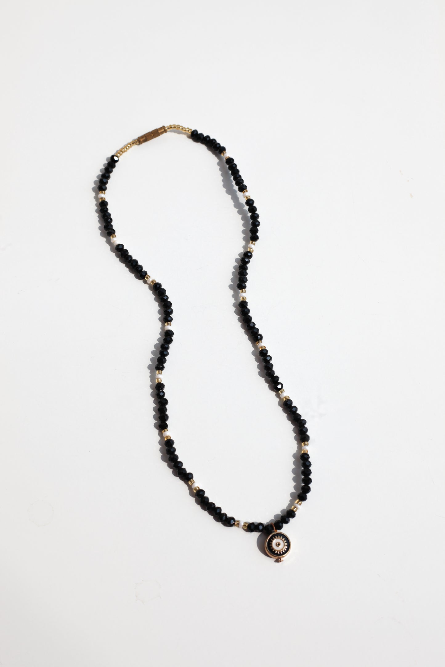 Necklace with black beads and a evil eye pendant on a white background