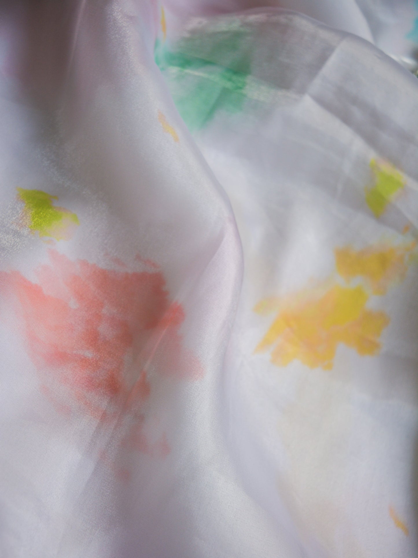 Close-up of a white organza fabric with colorful abstract patterns.