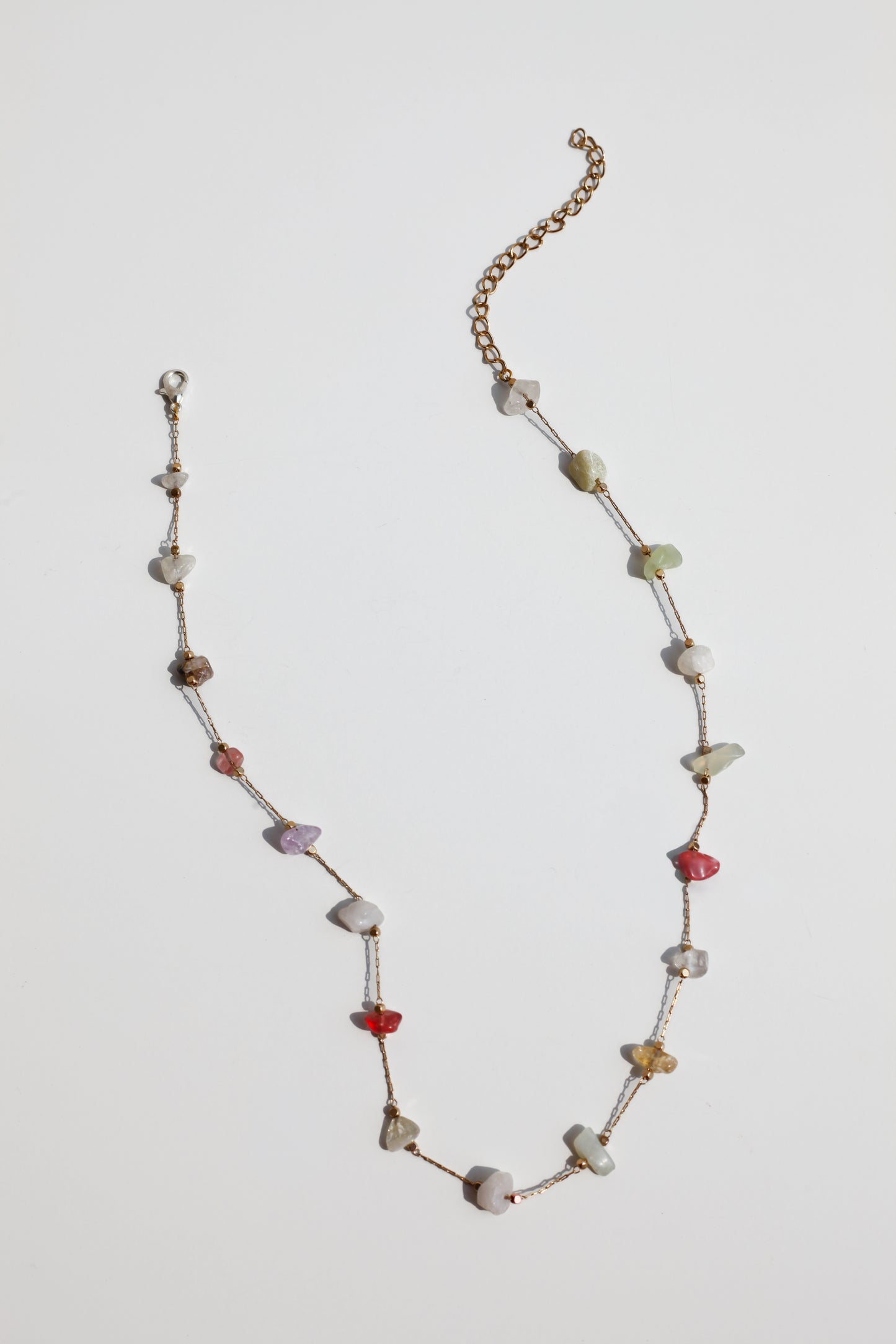 Necklace with multicolored stone on a light gray background