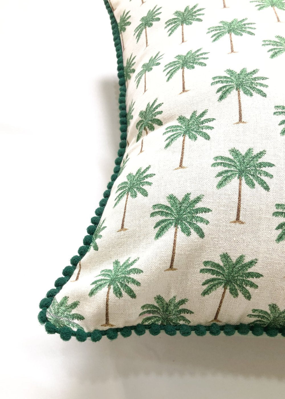 Close-up of palm print on a off-white cotton cushion cover. Handcrafted detailing with pompom lace on sides for a luxurious touch.