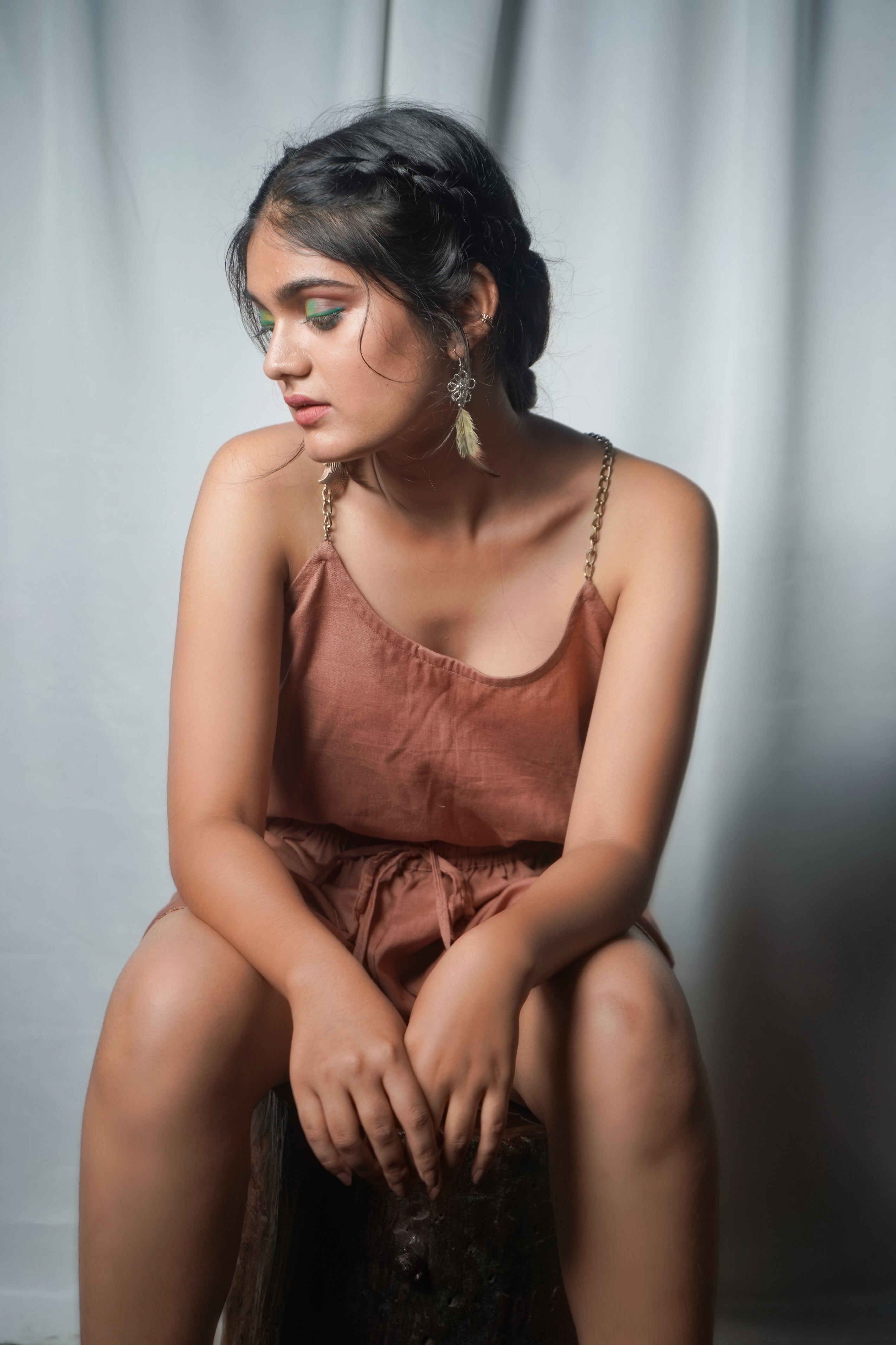 Woman in a brown cotton-linen co-ord set sitting against a plain background