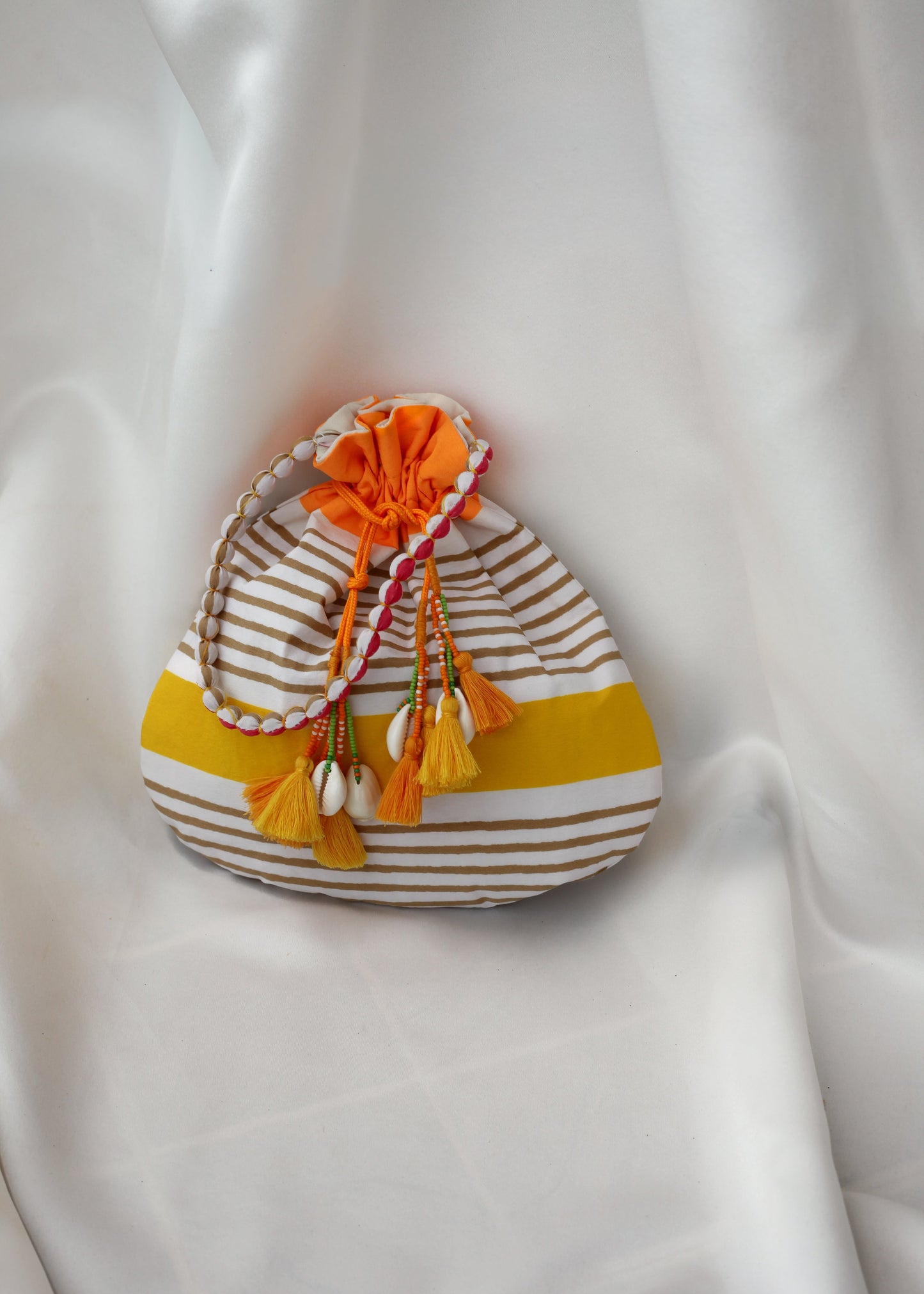 Striped fabric drawstring bag with decorative tassel tie-up on a white fabric background