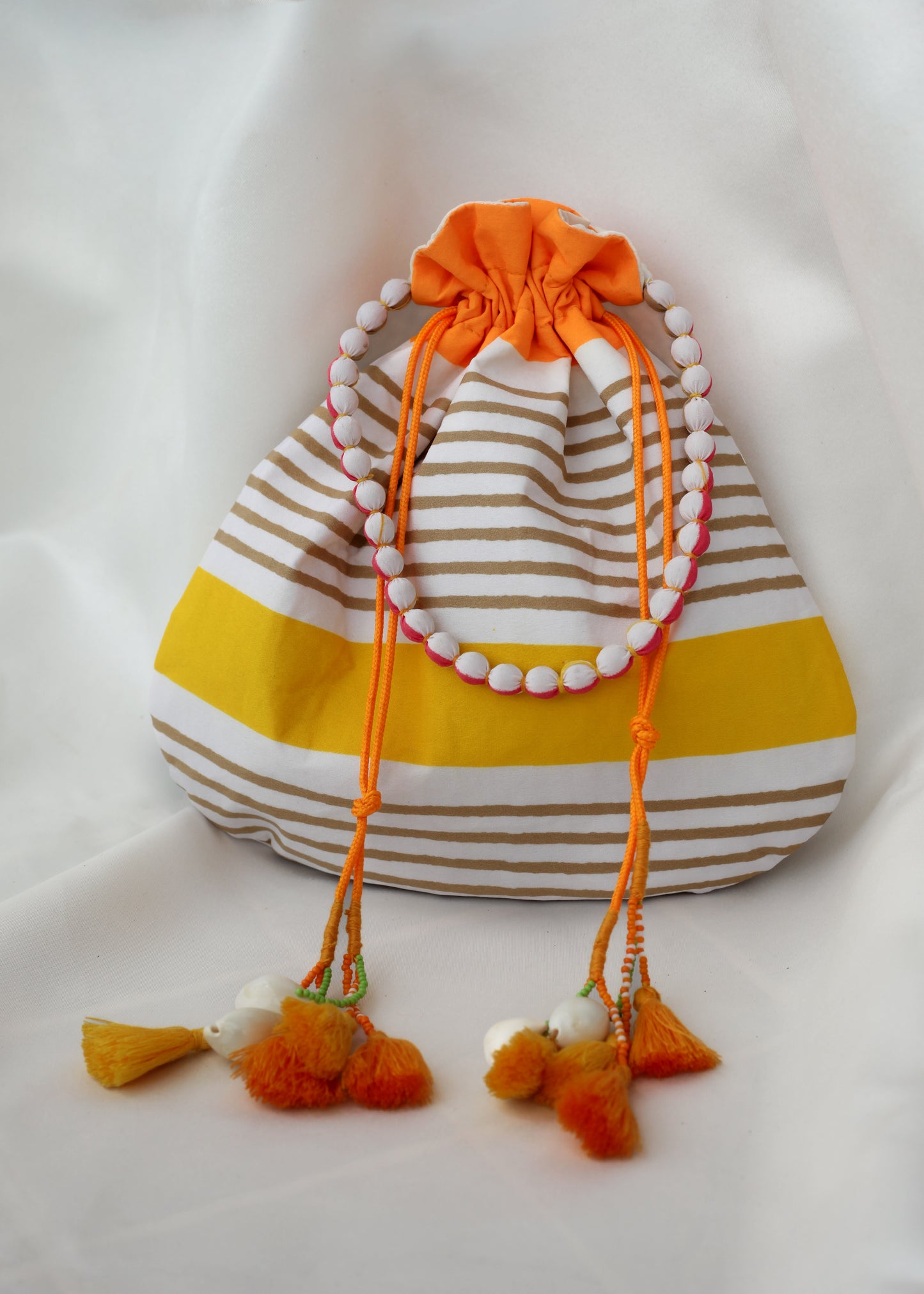 Striped drawstring bag with tassels on a white background