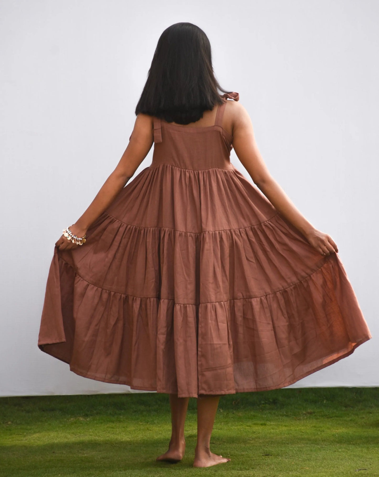 Back view of brown cotton-linen tiered midi dress showing dress flare.