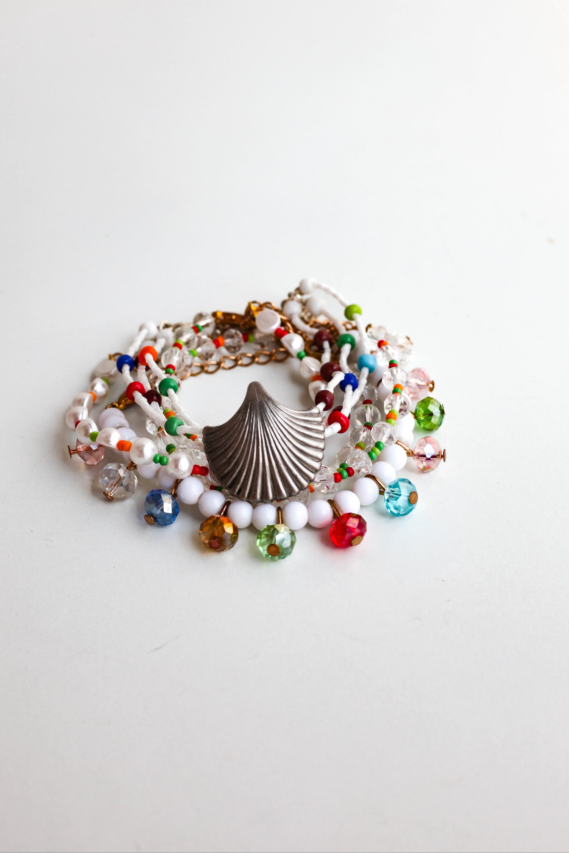 Colorful beaded bracelet with a shell charm on a white background