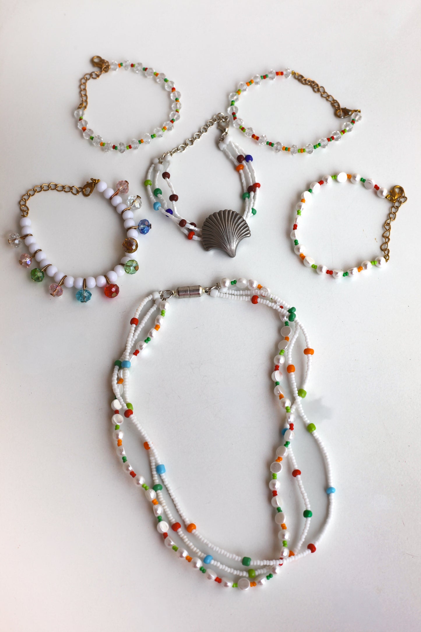 Set of colorful beaded jewelry including a necklace and bracelets on a white background
