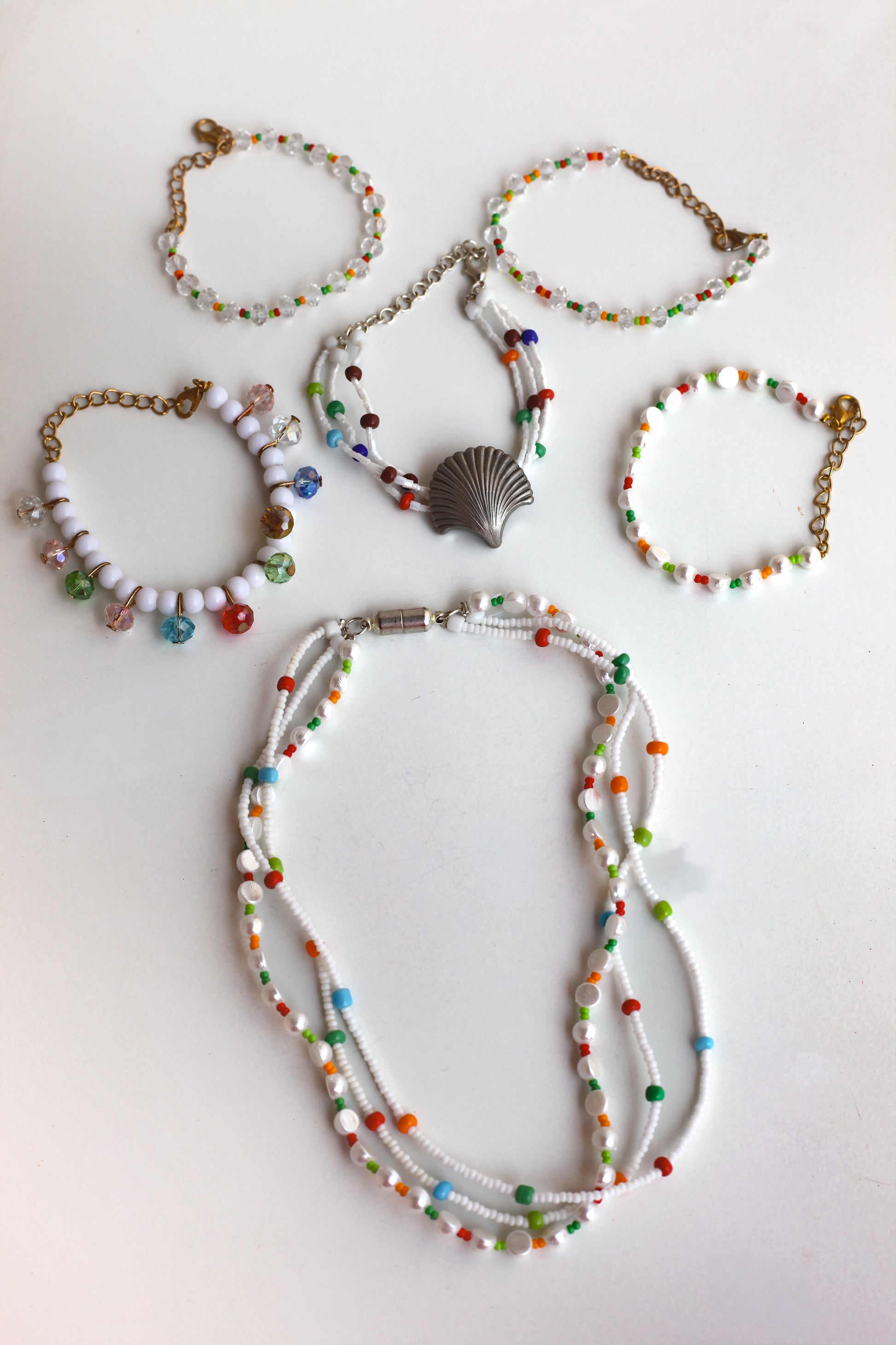 Set of colorful beaded jewelry including a necklace and bracelets on a white background