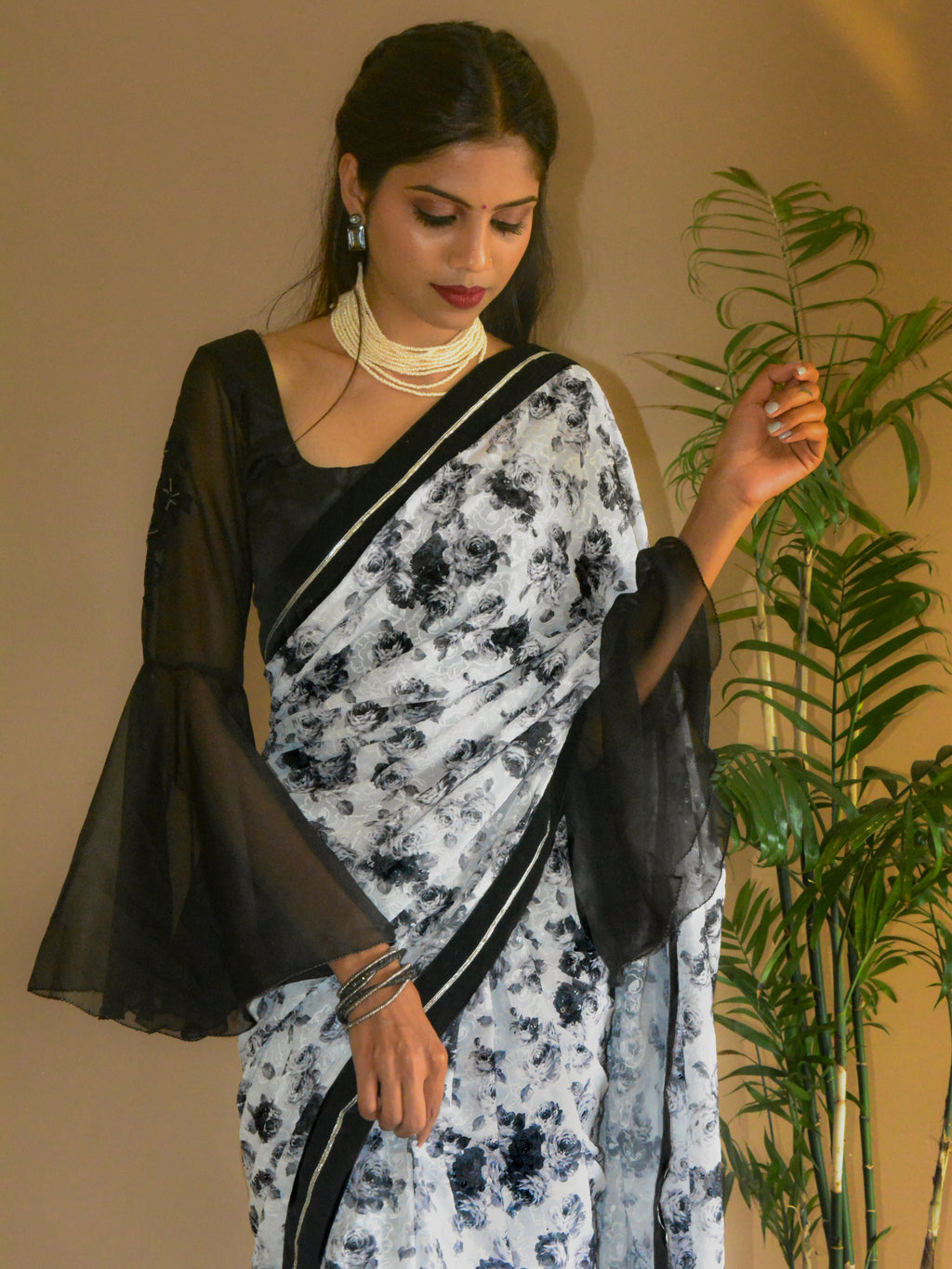 Close-up of a Model wearing Guldasta Saree featuring black and white rose print, intricate self-tone white embroidery, and subtle transparent sequins, with a black velvet and silver gotta patti border.