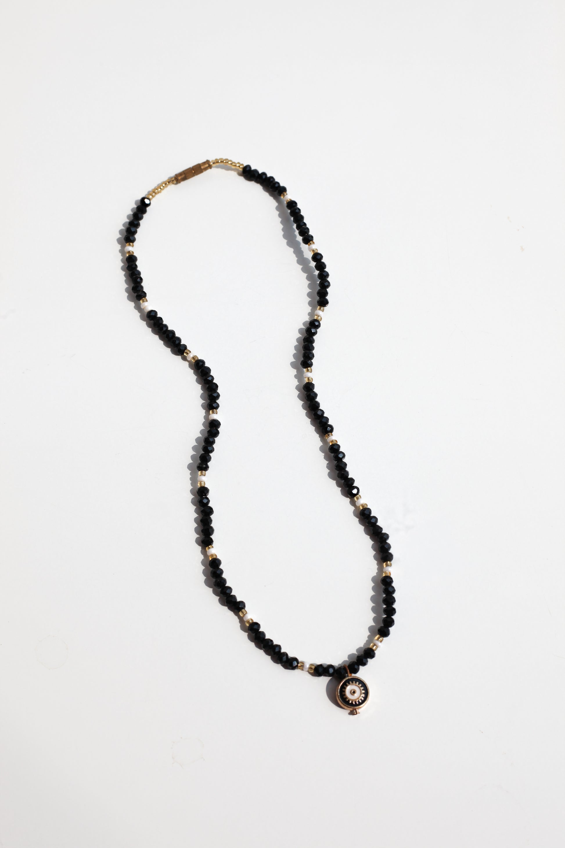 Necklace with black beads and a evil eye pendant on a white background