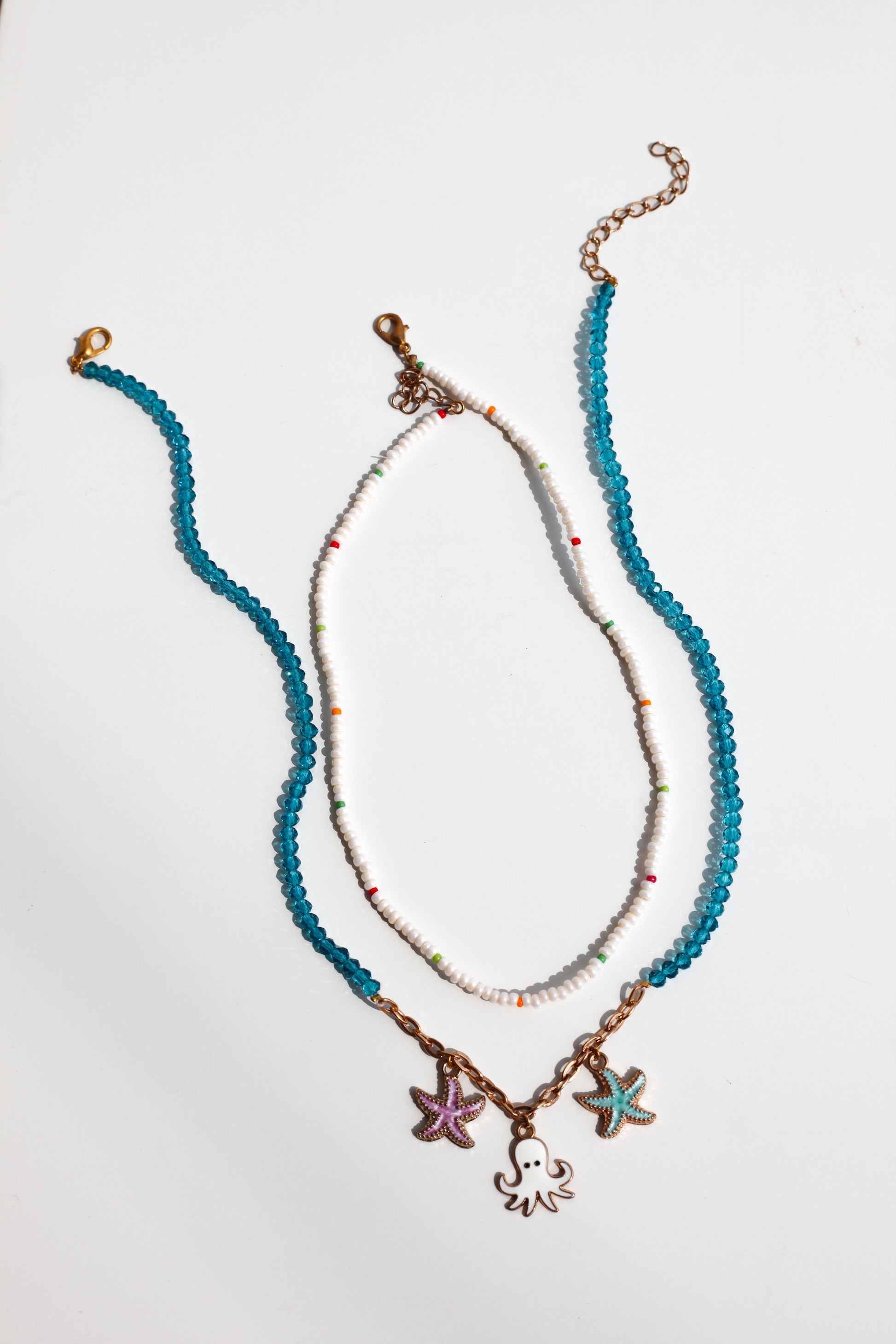Two beaded necklaces with starfish and octopus charm on a light gray background