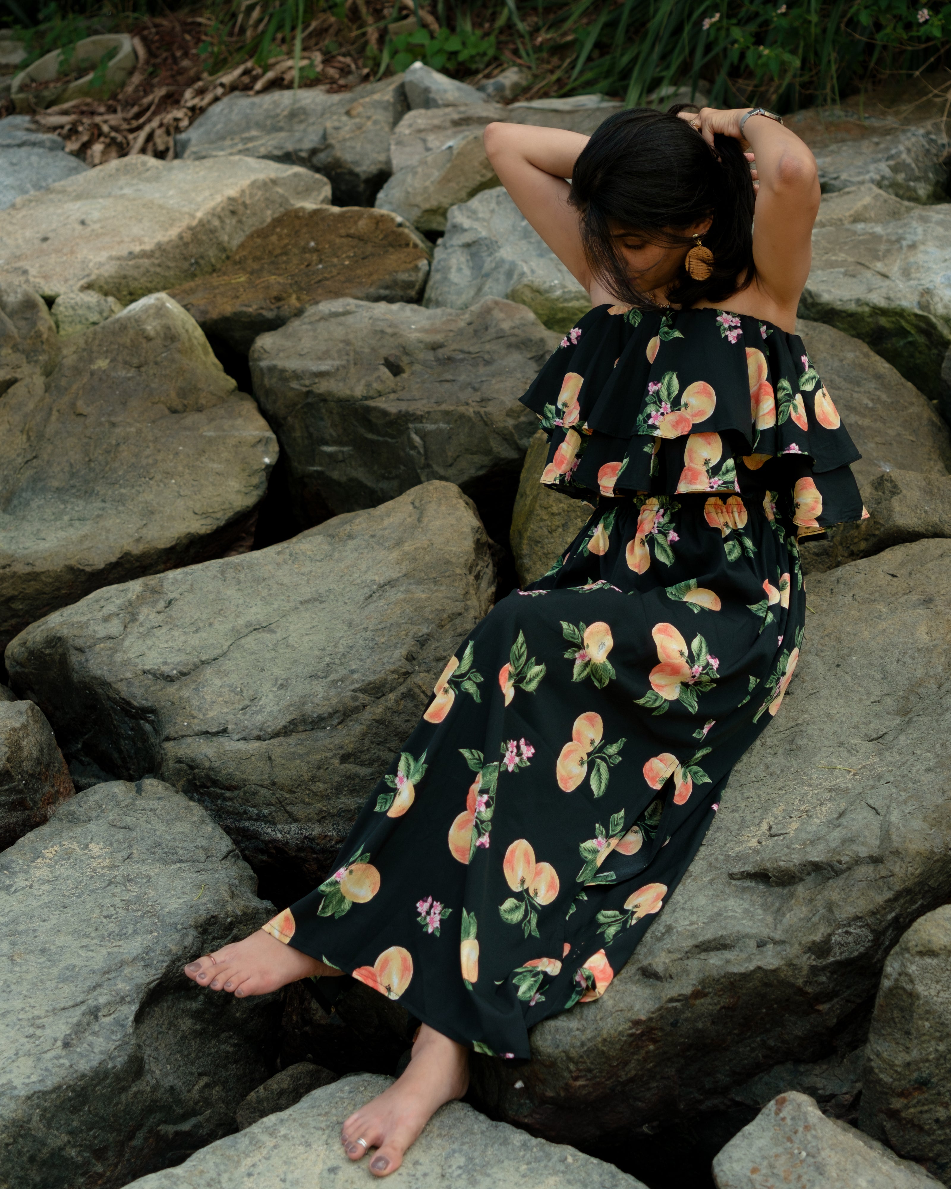 Woman in a black printed beach co-ord set sitting on rocks by a body of water in Sentosa Island Singapore