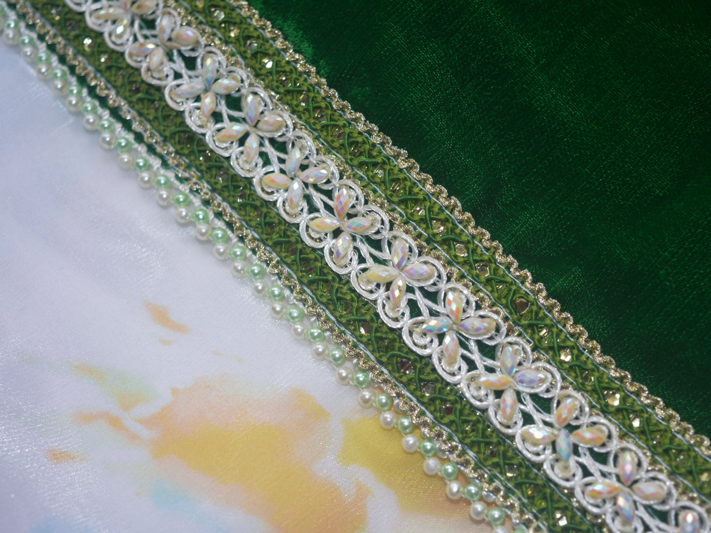 Decorative lace trim with floral patterns and beads on a green kurta fabric