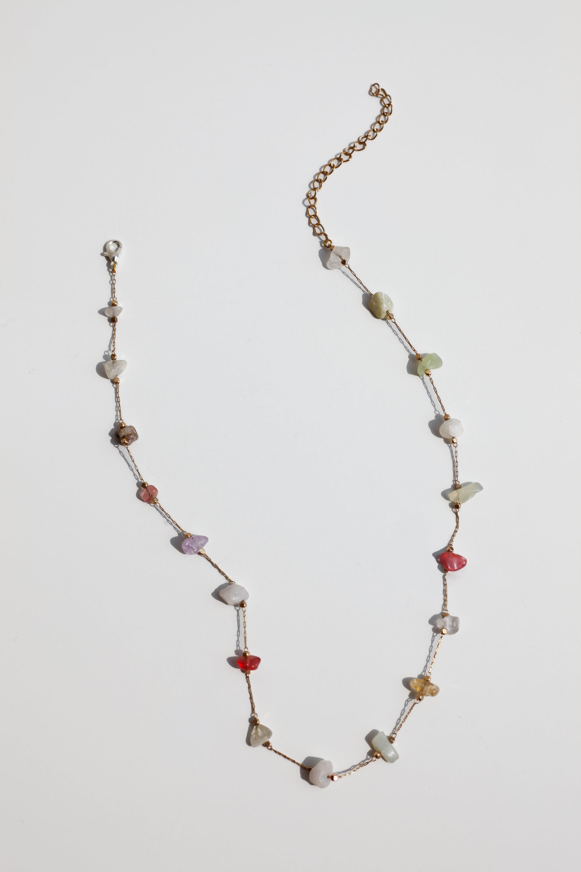 Necklace with multicolored stone on a light gray background