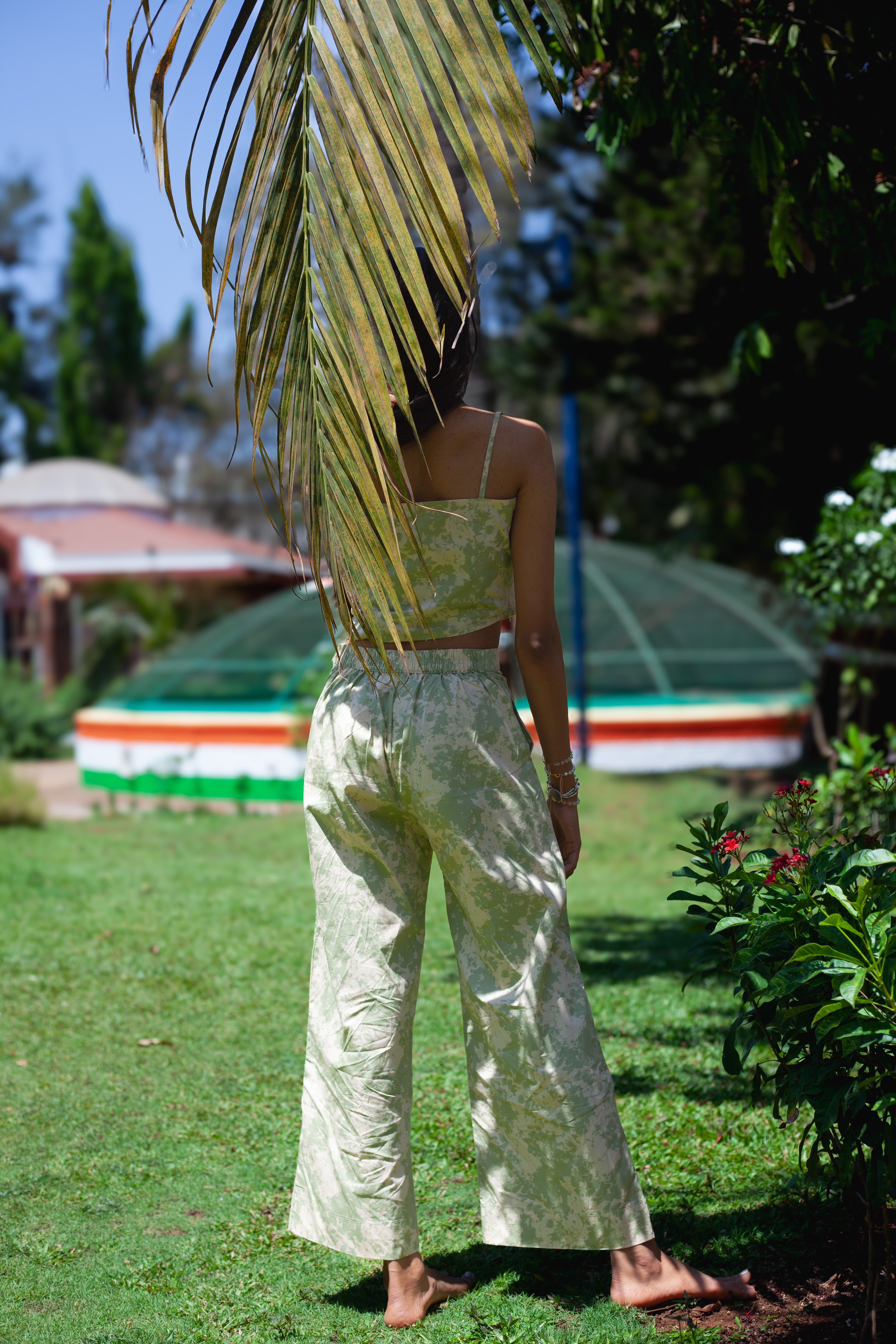 Back view of printed sage green trousers in poplin from the Pista Swirl Set, showing flare and elasticated waist belt, styled with matching crop top