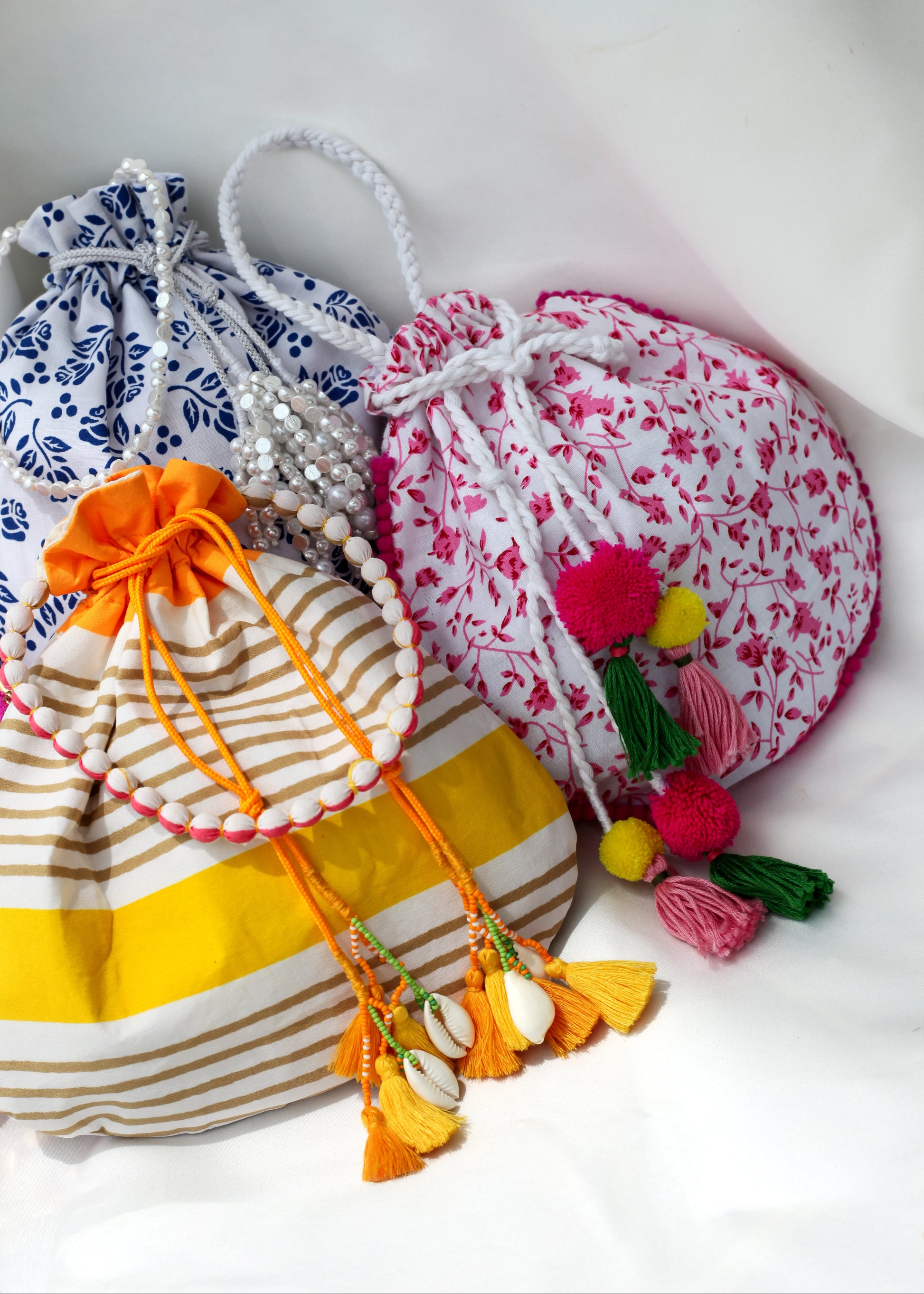 Collection of colorful drawstring bags with decorative elements on a white background
