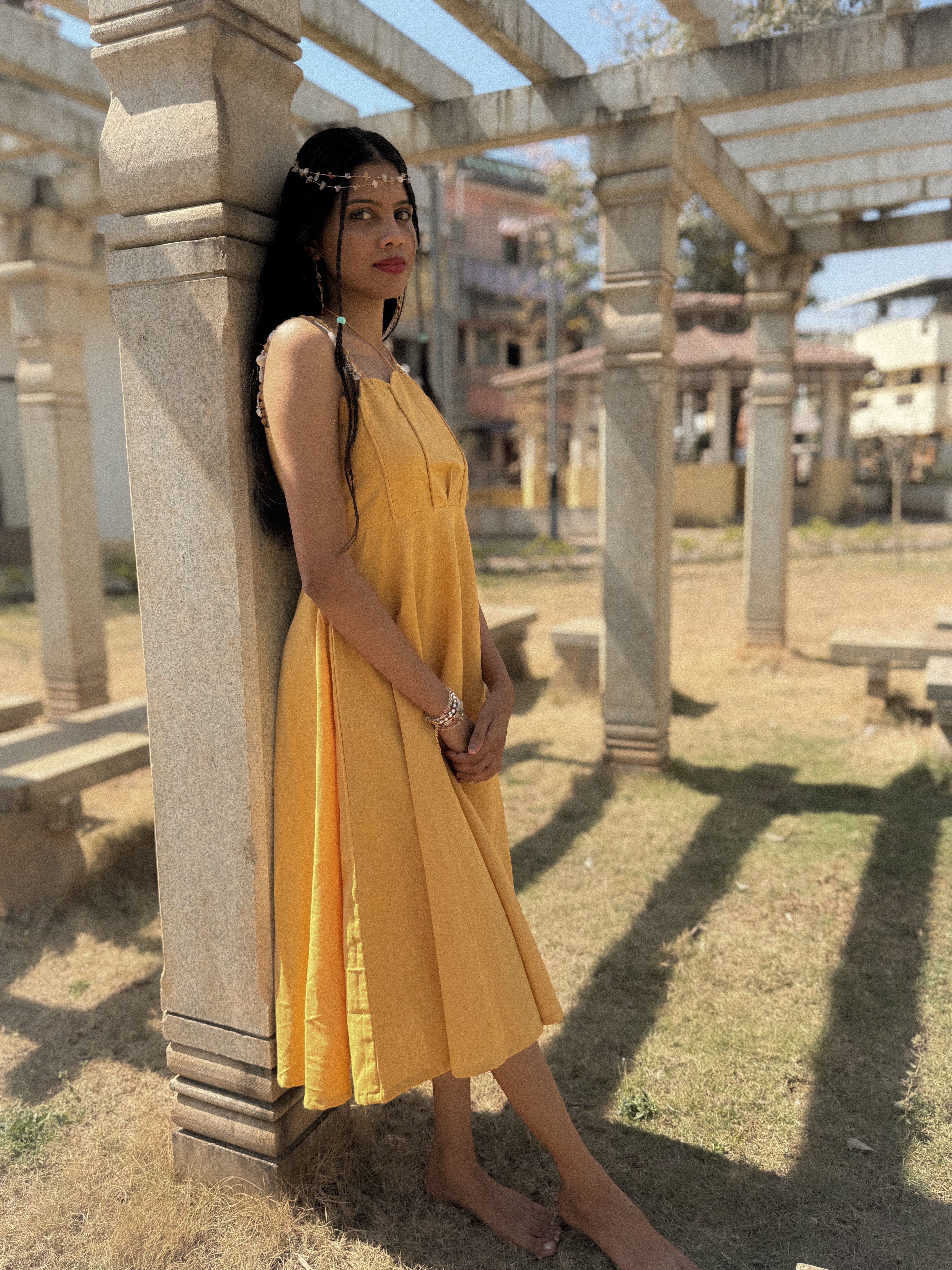 Side view of the yellow cotton-linen Sandshells midi dress showing the drape and length.