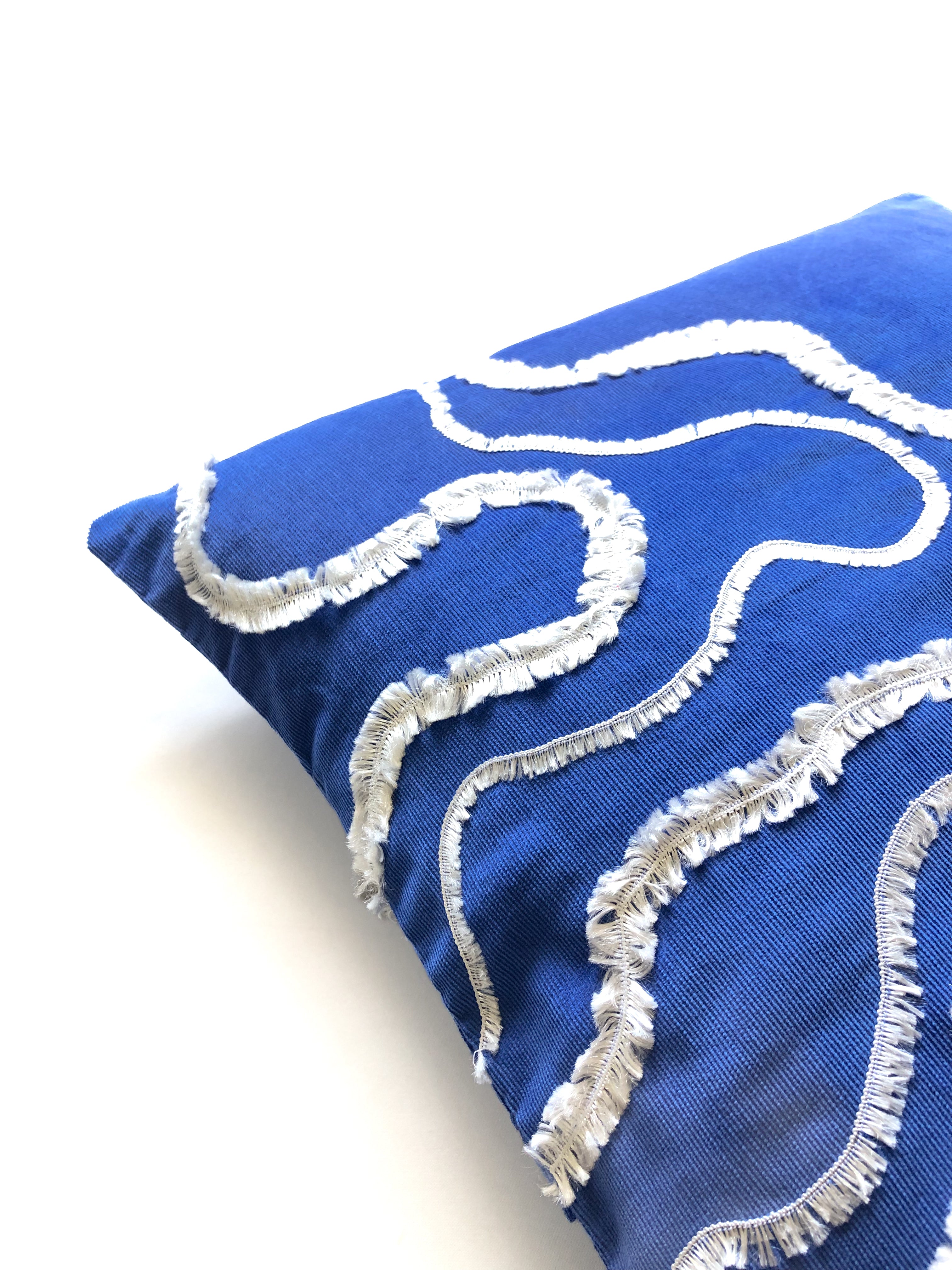 Close-up detail of cobalt blue cotton cushion cover with white textured wave embroidery, inspired by ocean waves. This modern, handcrafted cushion is perfect for coastal, boho, or minimalist home décor. Ideal for sofas, beds, and lounge spaces, adding a stylish and elegant touch.