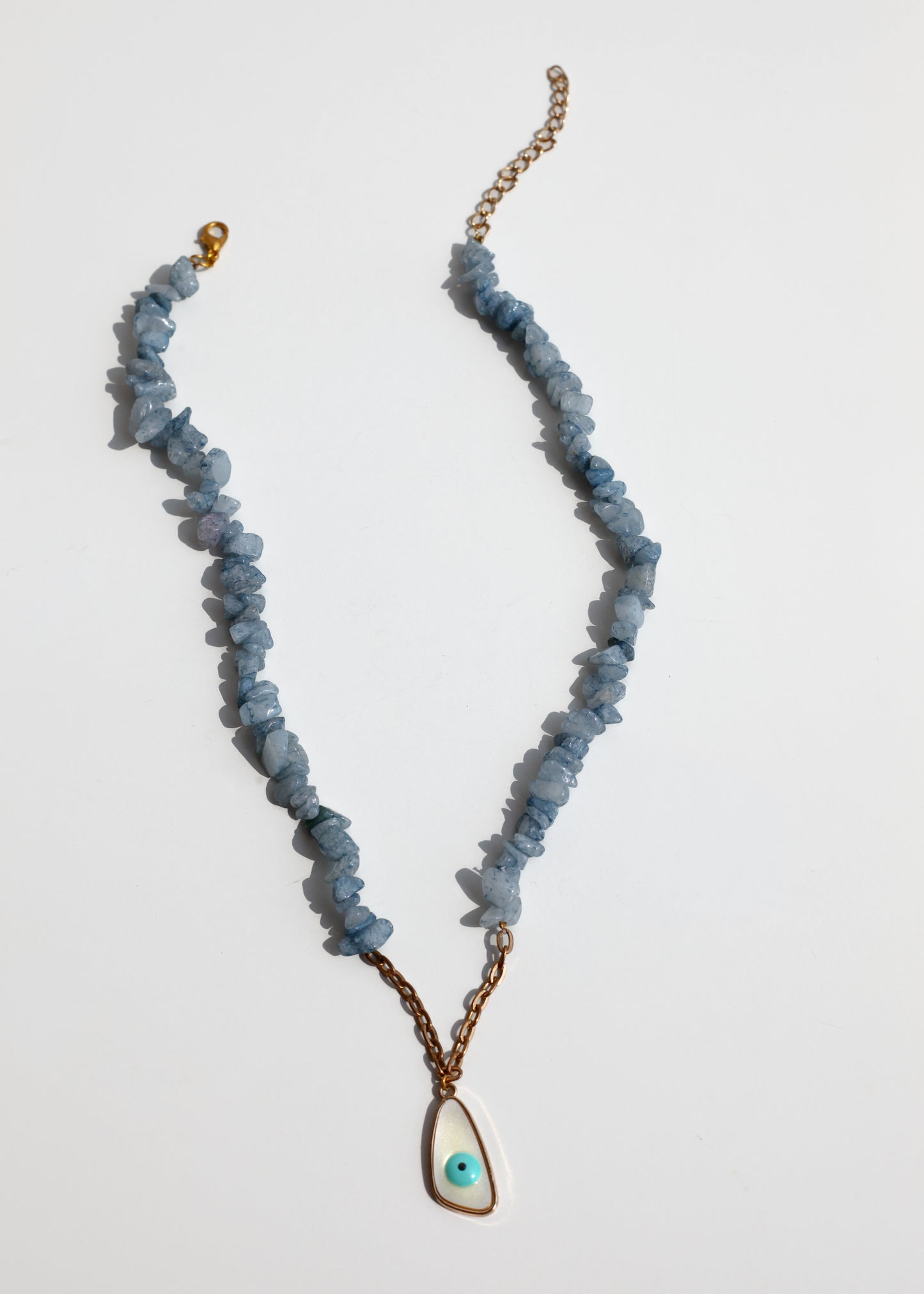Necklace with blue beads and a gold chain on a light gray background