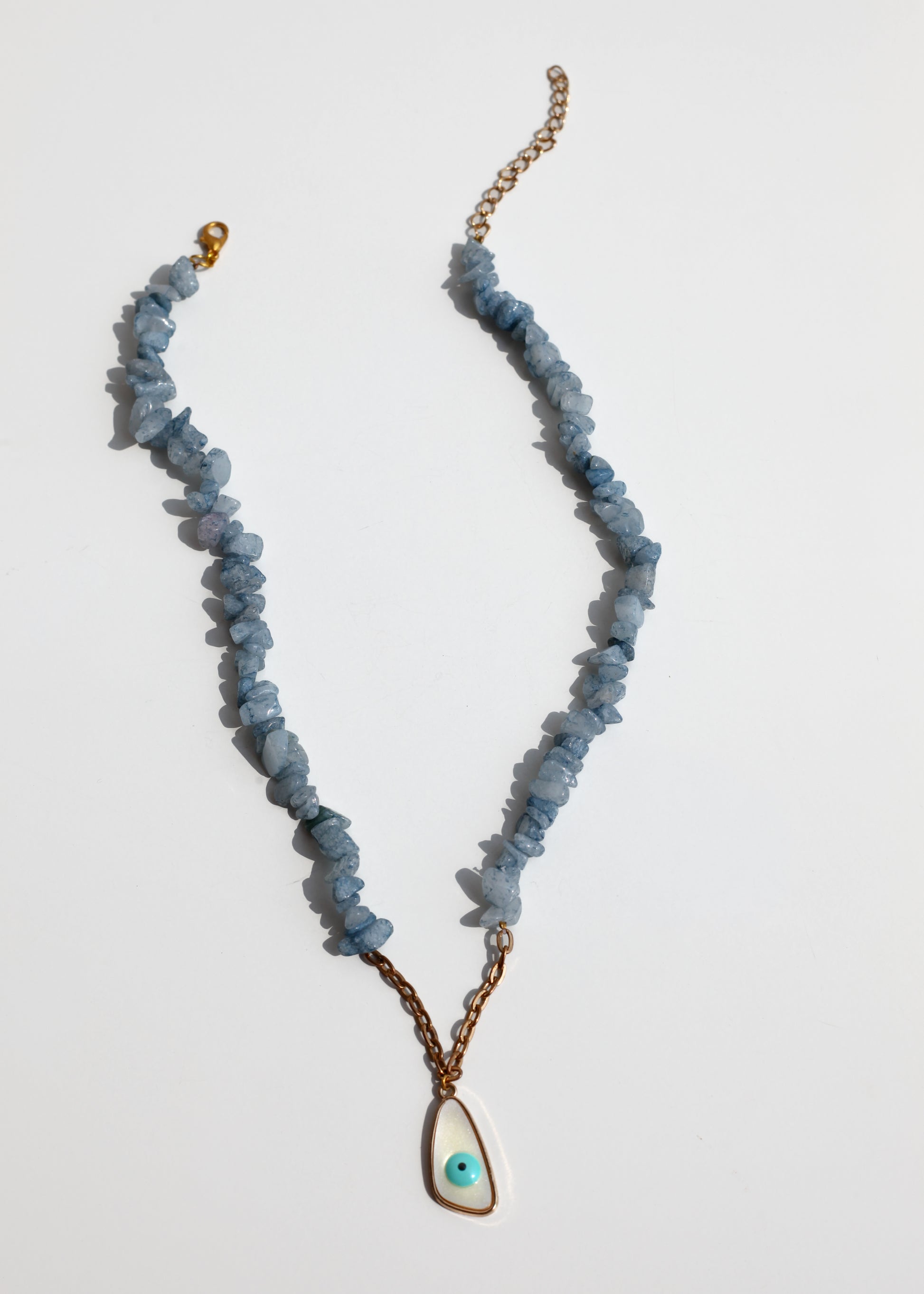 Necklace with blue beads and a gold chain on a light gray background