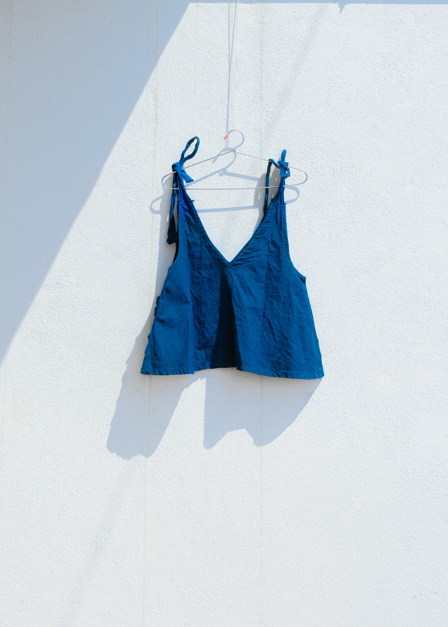 Back view of blue cotton linen crop top with tie shoulder straps and V neckline