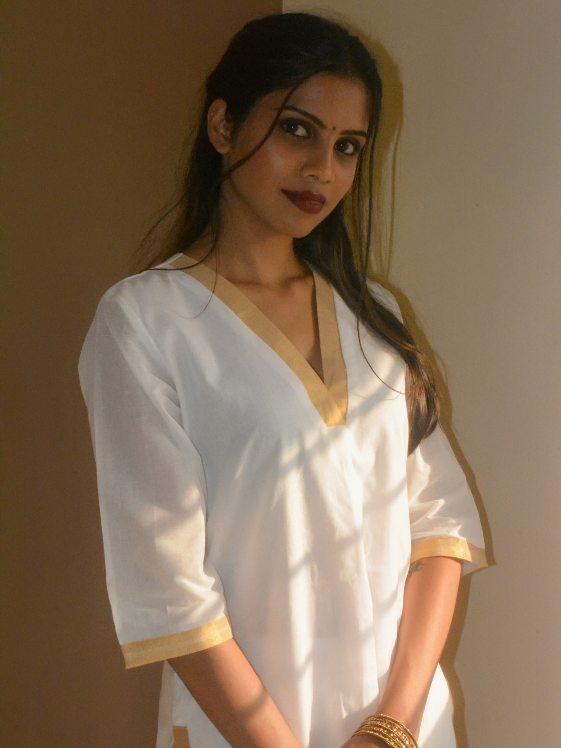 White cotton Ila kurta with V neckline and three quarter sleeves, styled for a festive look.