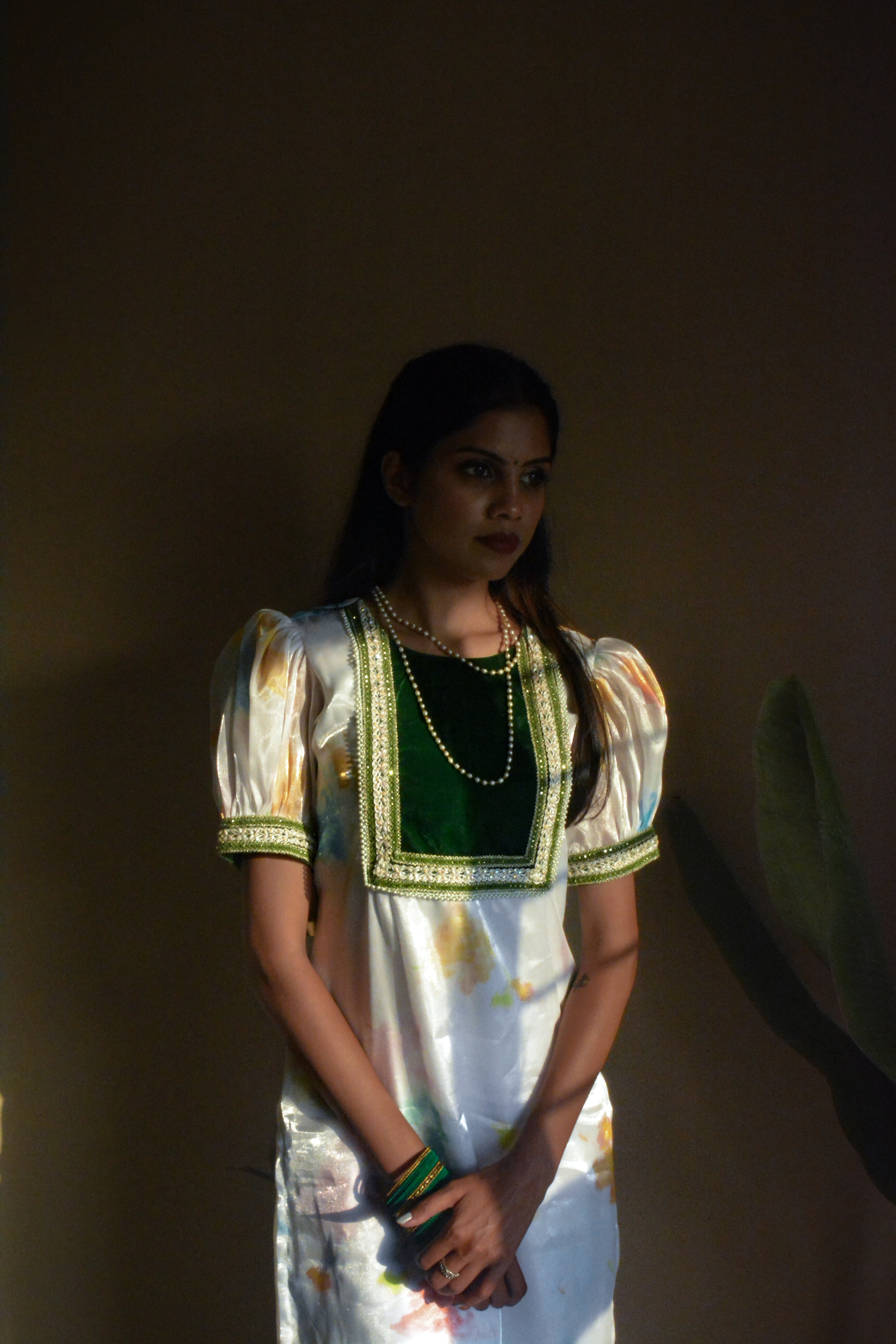 Woman wearing a white organza traditional kurta with a dark background