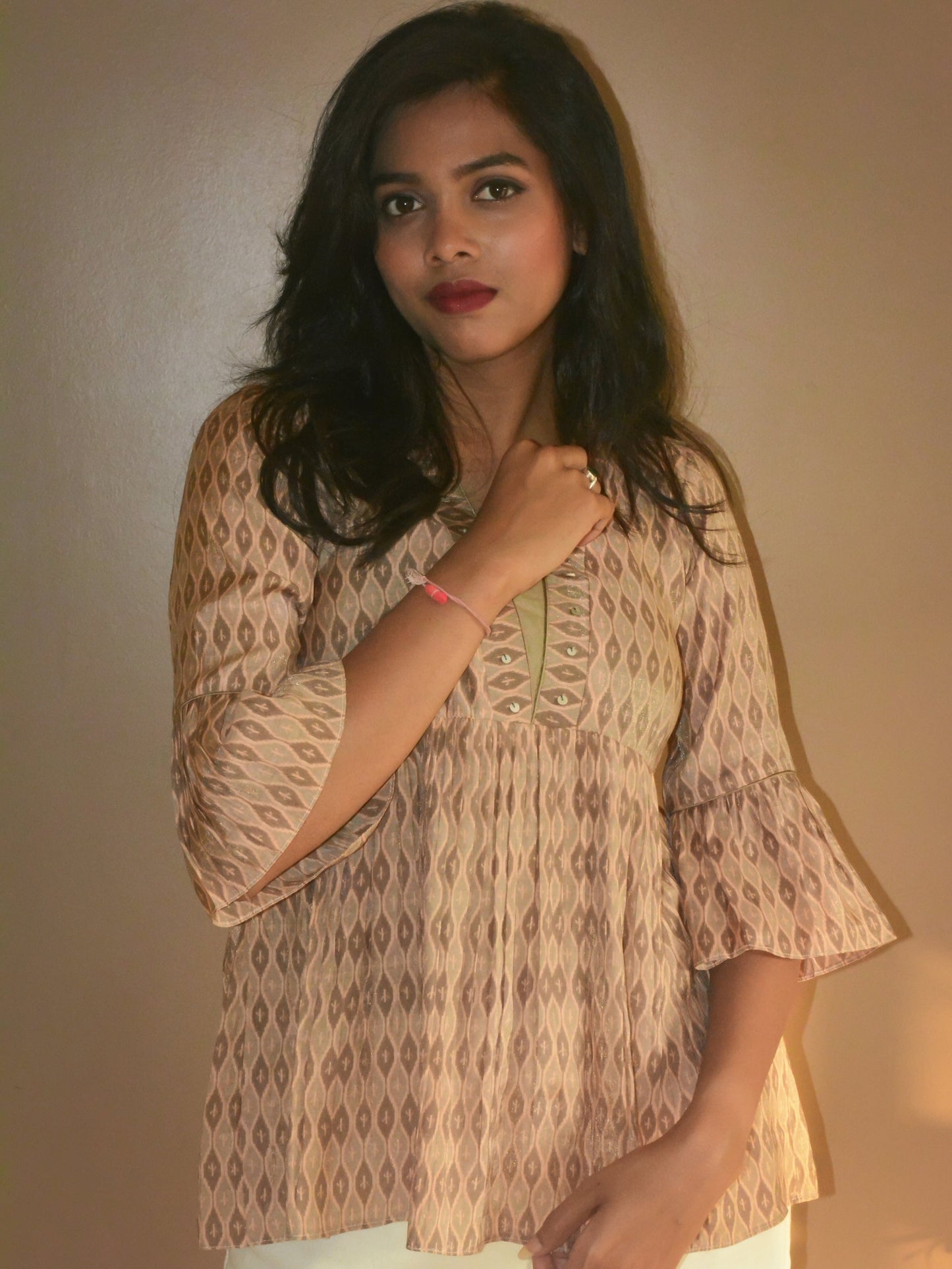 Woman wearing a printed muslin-silk beige tunic against a plain background