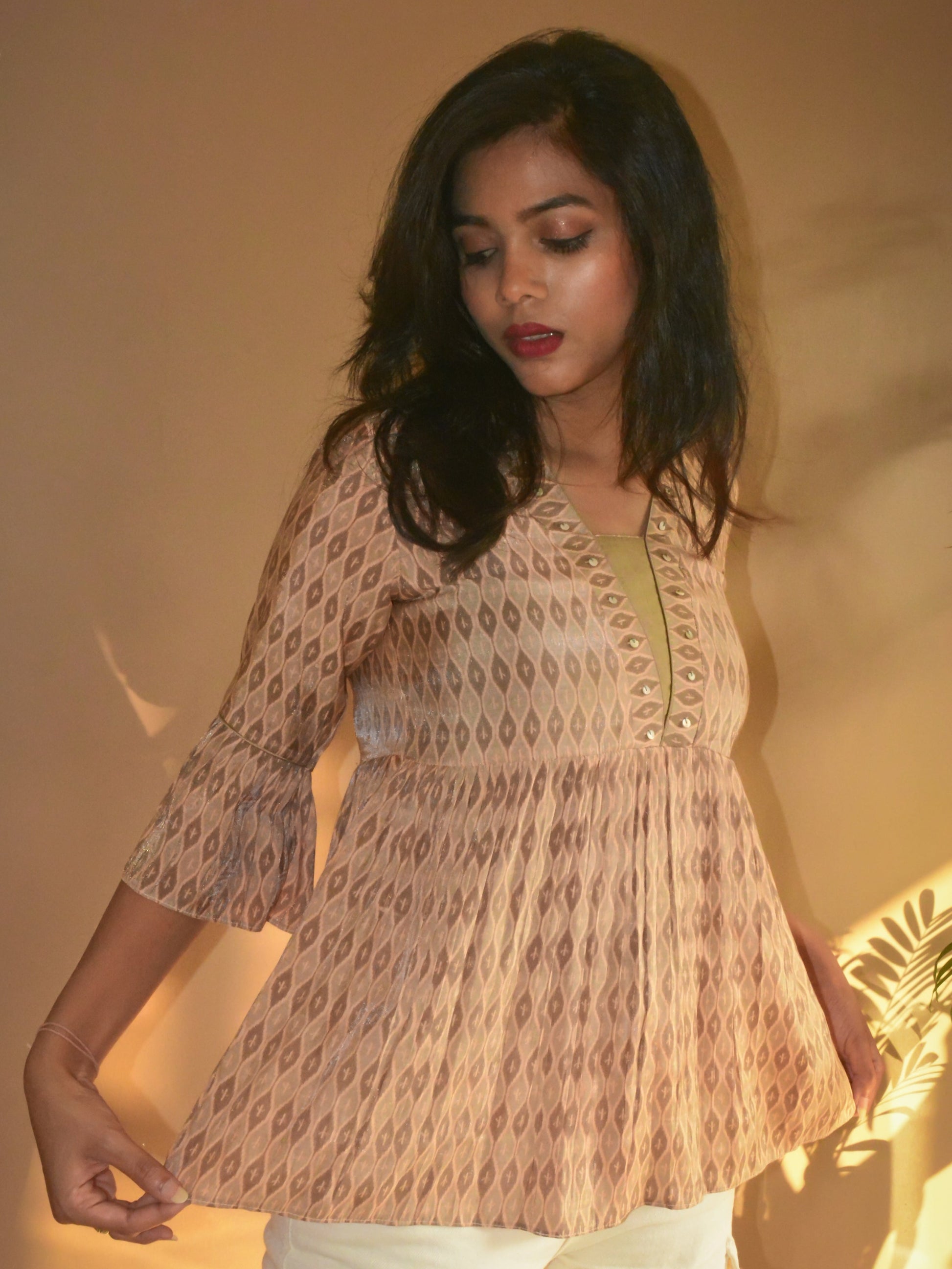 Woman wearing a beige printed muslin-silk tunic with a warm, soft light background