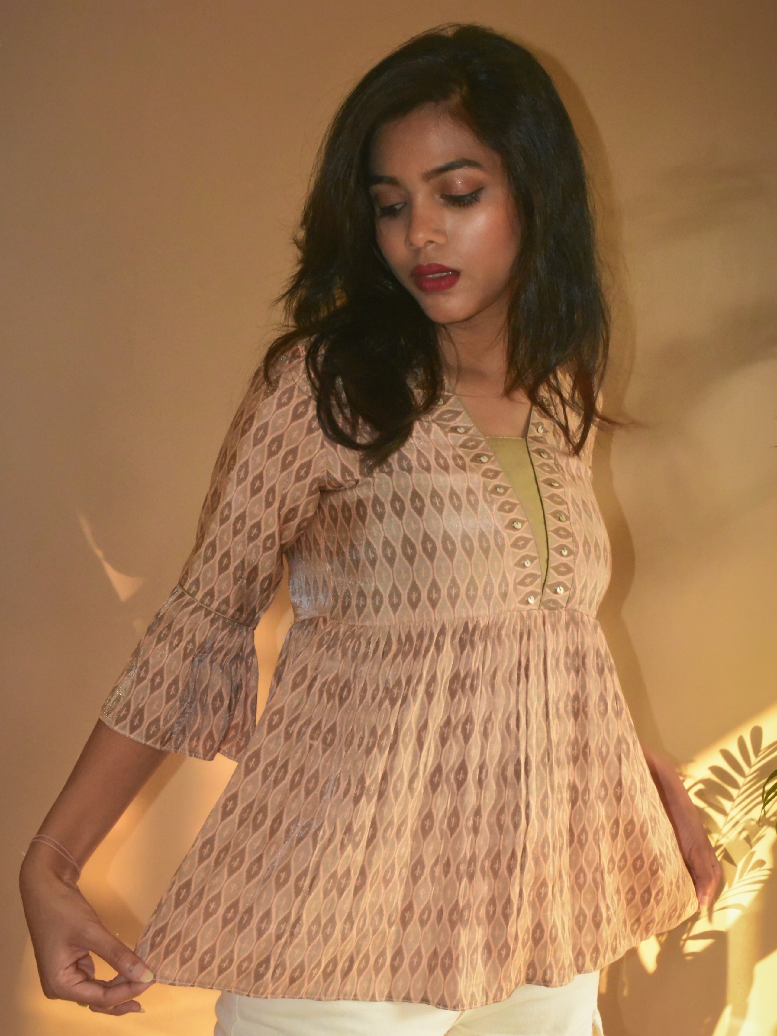 Woman wearing a beige printed muslin-silk tunic with a warm, soft light background
