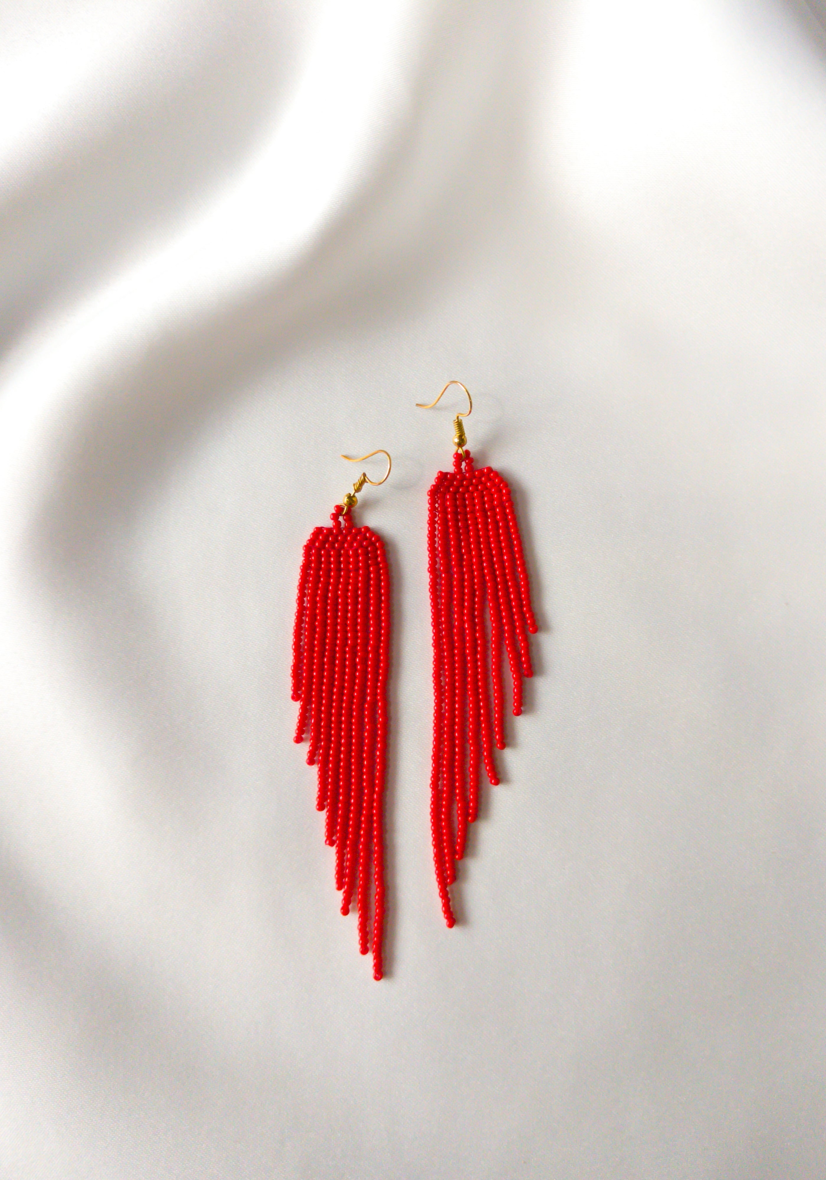 Wings of Love earrings in rich red placed on white background